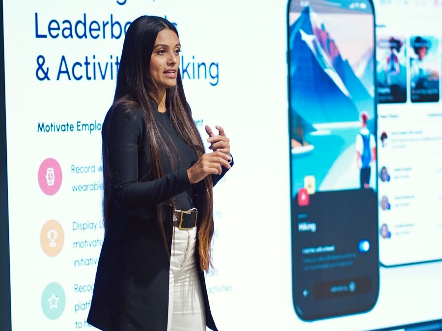 Ivy Forero presenting a product keynote on stage in front of a projected app interface